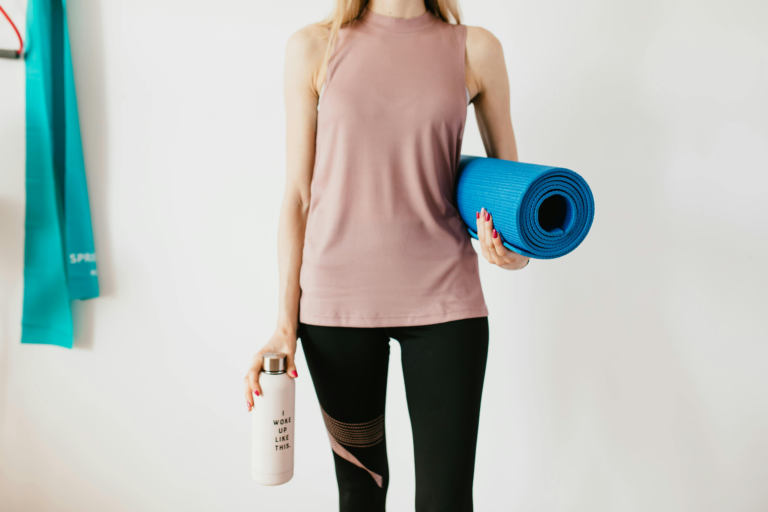 Γυναίκα κρατάει mat για pilates και θερμός